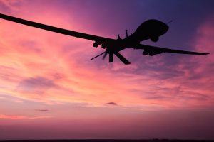 a surveillance drone flying over a sunset